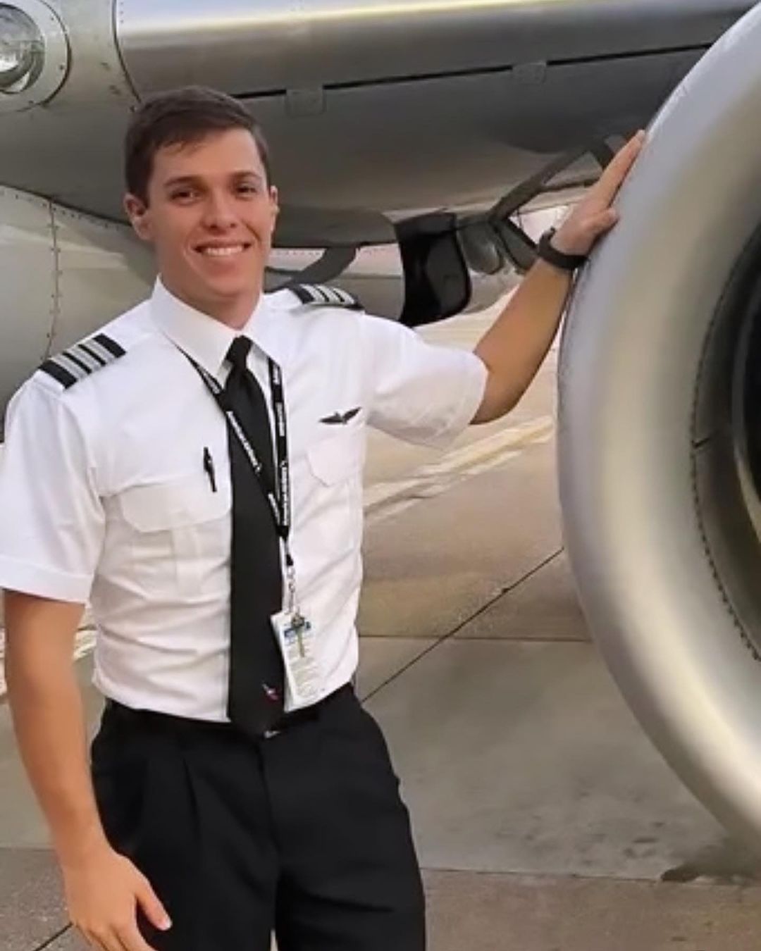 Airline pilot posing next to an airliner engine